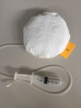 image of a quilted cushion with a tube extending from it and a syringe.