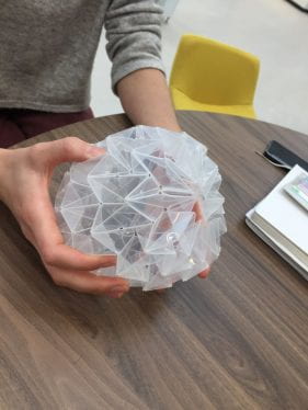 image of hands holding an angular sphere made from folded plastic.